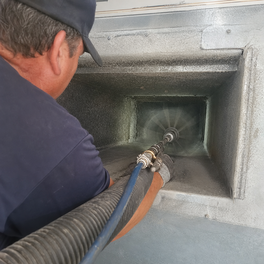 Technician using a rotating brush tool for professional air duct cleaning.